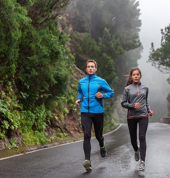 Rain run fit people training jogging in rain weather wearing cold clothing running outdoors in nature autumn season. Active couple on wet park trail jogging. Asian woman, Caucasian man athletes. ID:351523517